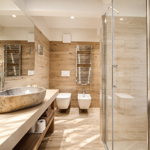 Bagno dell'Hotel Plaza con rivestimenti effetto legno, lavabo in pietra naturale, doccia in vetro e arredi su misura realizzati da Arredamenti Depal.
