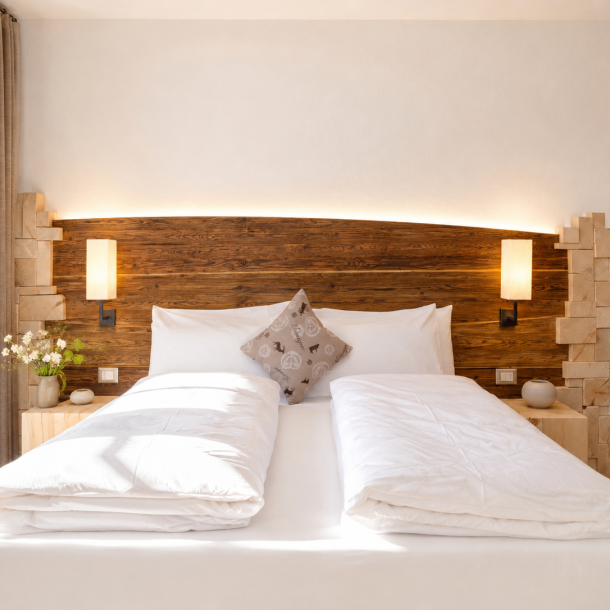 Camera dell'Hotel Plaza con testiera curva in legno bruciato retroilluminata, comodini in legno massello e dettagli di design alpino contemporaneo.