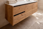 Mobile bagno sospeso in legno naturale realizzato su misura, con lavabo integrato bianco, specchio minimal e pensile coordinato. La luce proveniente dal lucernario valorizza le venature del legno e crea un ambiente bagno luminoso, elegante e accogliente in stile alpino contemporaneo.