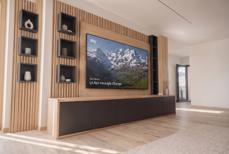 Parete TV su misura in stile contemporaneo con rivestimento a doghe in legno, nicchie decorative nere, mobile basso sospeso e finiture a contrasto. Un progetto che unisce funzionalità, design e calore naturale.