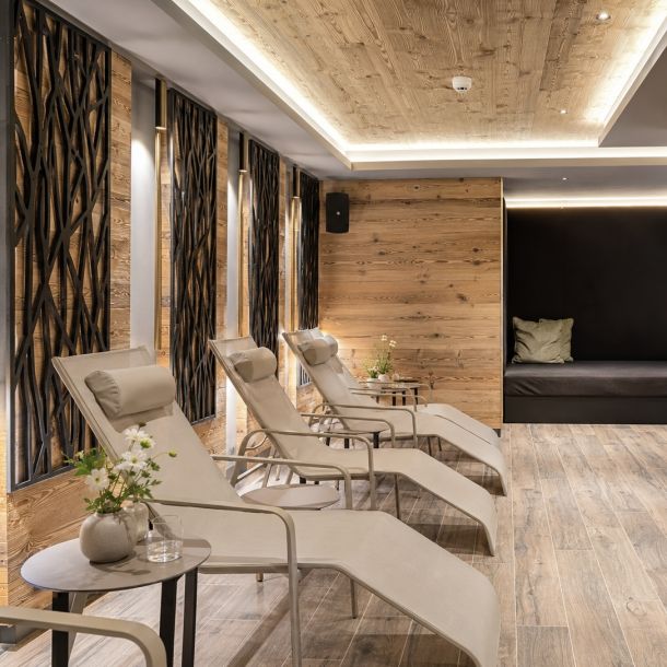 Sala relax di centro benessere con lettini ergonomici, boiserie in legno, illuminazione soffusa e atmosfera elegante dedicata al wellness.